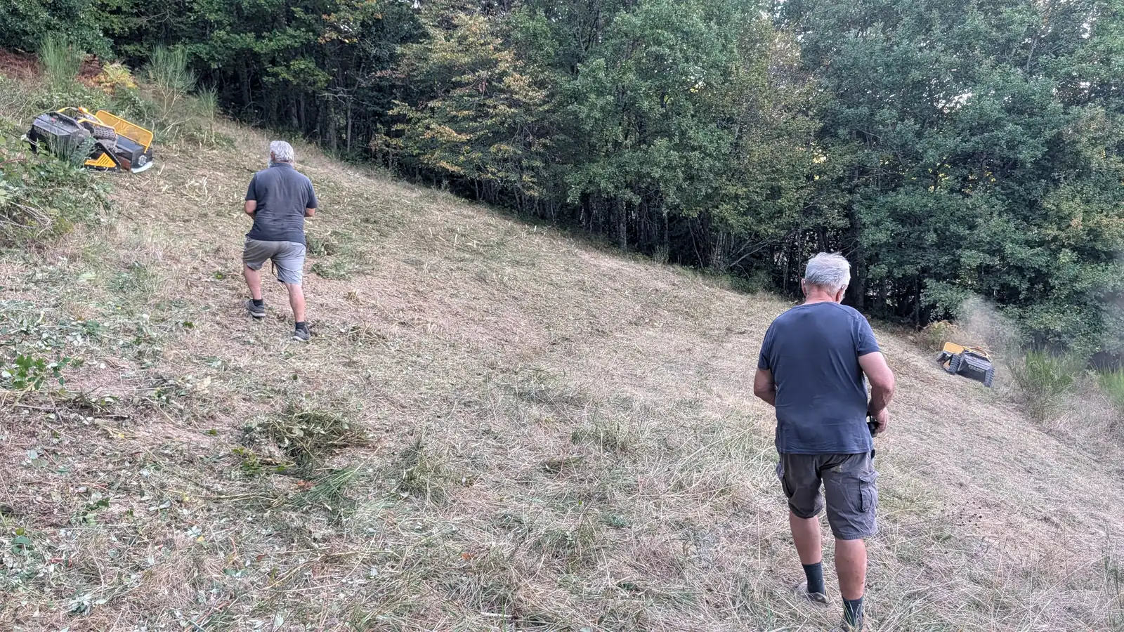 Deux opérateurs pilotant à distance pendant que les broyeurs travaillent un dévers, en Aveyron